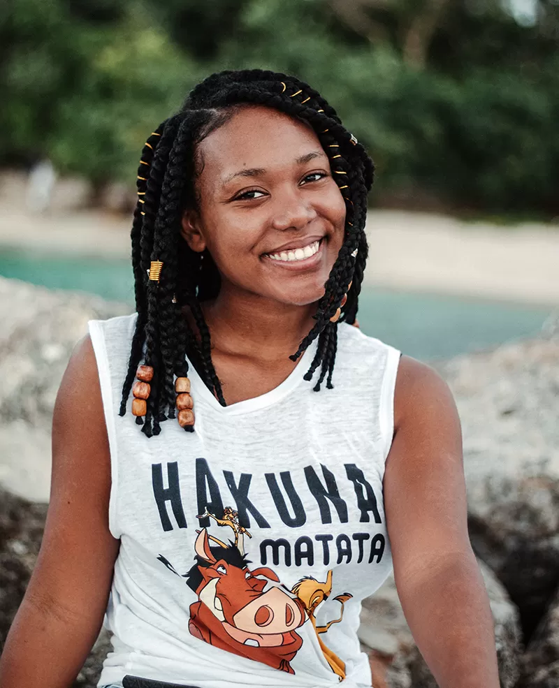 Smiling black woman in stylish apparel on mount near lake